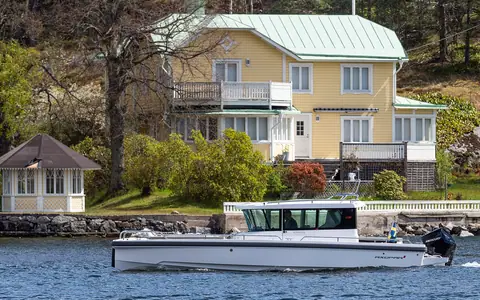 Axopar cabin boat passing a waterfront house near Vaxholm, Sweden
