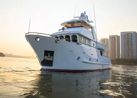 Bering 65 expedition trawler at sunset near a city skyline