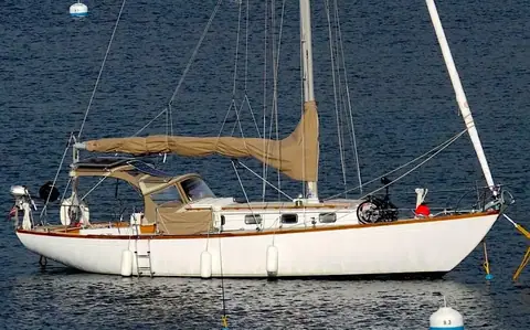 Alberg 37 sloop at a mooring showing its long overhangs, low trunk cabin and cockpit dodger