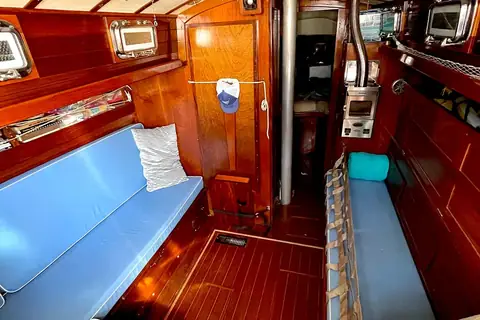 Alberg 37 main cabin with varnished wood joinery and blue settee cushions