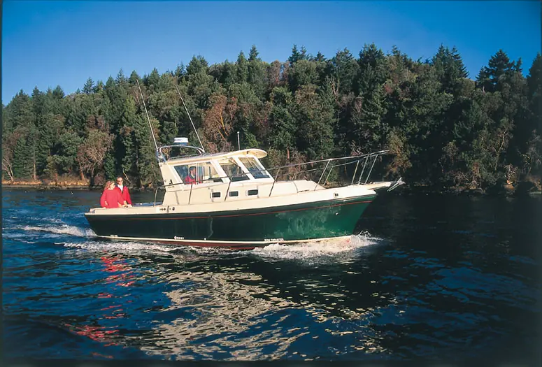 Albin 28 Tournament Express running along a wooded shoreline on calm water