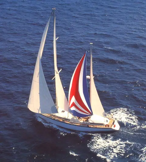 Amel Super Maramu ketch reaching on blue water with a red, white and blue mizzen staysail set