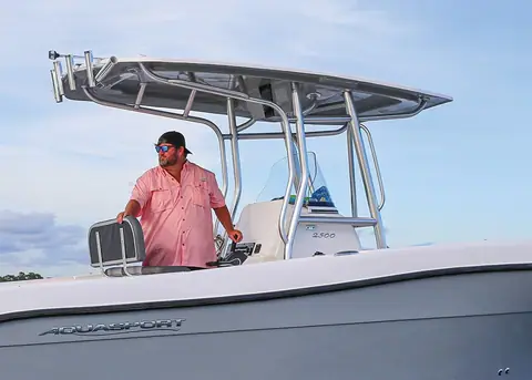 Aquasport 2500 CC helm with the T top, leaning post and an angler at the wheel