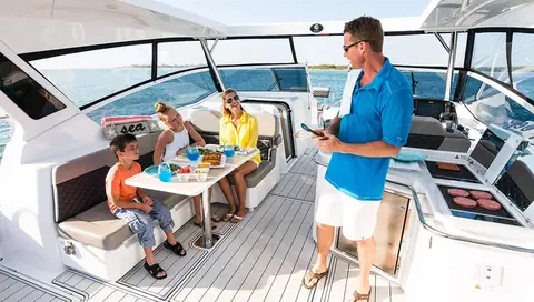 Aquila 36 Sport bridge deck with a family at the dinette and the helm to starboard
