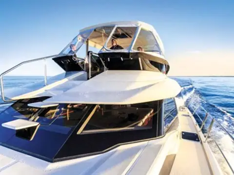 Aquila 44 underway with crew at the flybridge helm under the hardtop