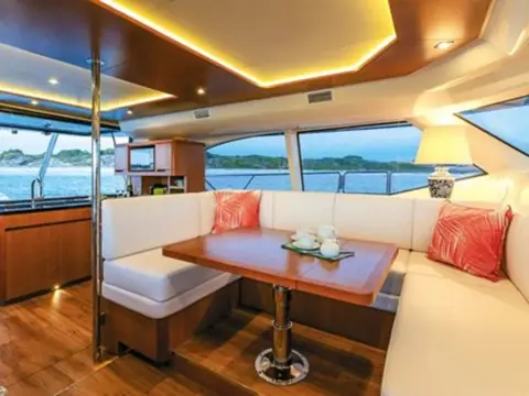 Aquila 44 salon with a U shaped dinette, wood table and wide panoramic windows