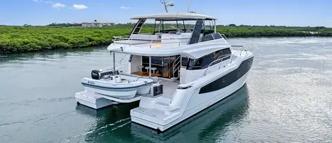 Aquila 50 Yacht at anchor off a mangrove shore with its tender on the aft platform
