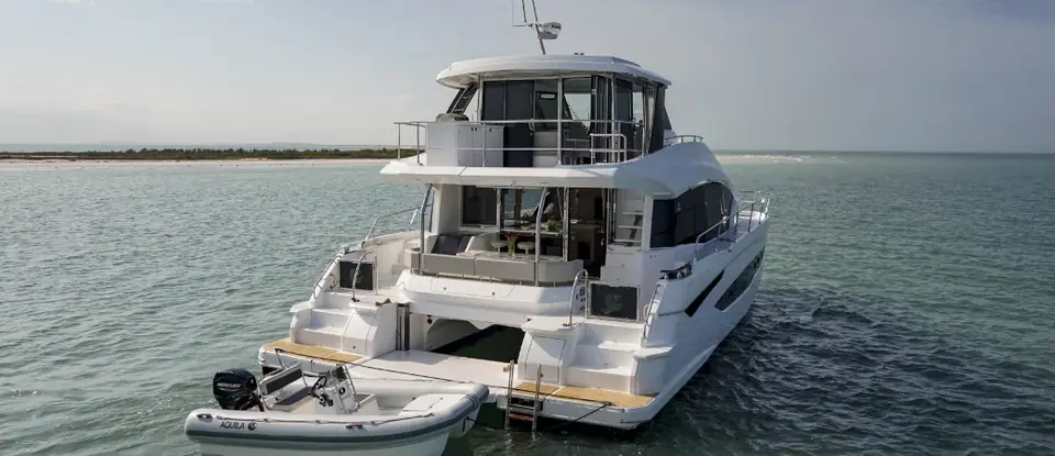 Aquila 54 Yacht at anchor seen from astern with a tender tied to the swim platform