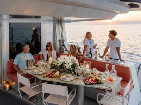 Arksen 85 aft deck with guests dining at a long table at sunset