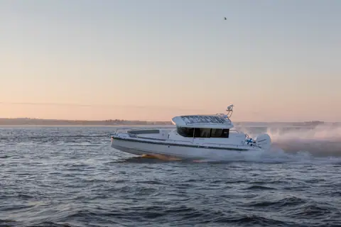 Axopar 28 Cabin running fast at sunset with spray off the stern