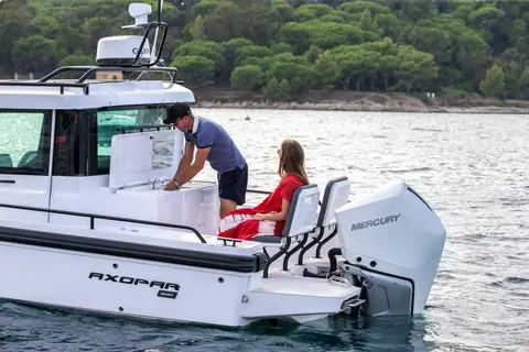 Axopar 28 Cabin aft cockpit with a couple by the Mercury outboard and cabin door