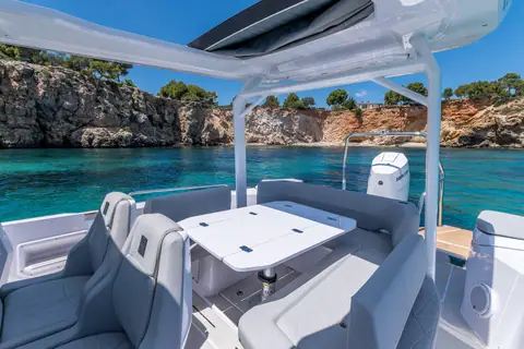 Axopar 29 Sun Top cockpit table and seating under the canopy, looking aft to the outboard