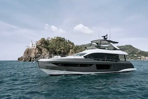 Azimut 68 at rest off a rocky headland with a lighthouse, seen from the starboard bow