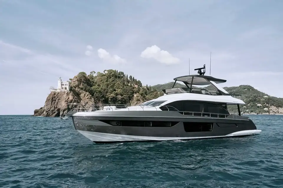 Azimut 68 at rest off a rocky headland with a lighthouse, seen from the starboard bow