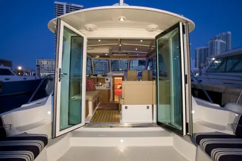 Back Cove 37 cockpit with glass doors open to the saloon at dusk