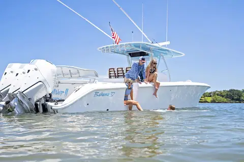 Bahama 37 at rest in shallow water with guests on the gunwale and the hull name visible