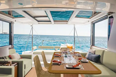 Bali 4.2 saloon with dining table and the tilting aft door raised open to the cockpit
