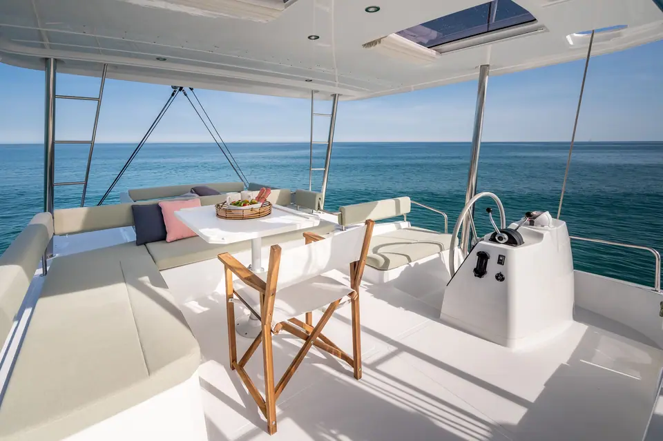 Bali 4.6 flybridge with helm station, lounge seating and table under the hardtop