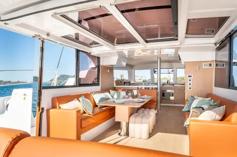 Bali Catspace saloon with orange settees, dining table and galley forward