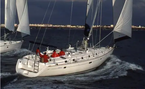 Beneteau 50 sailing upwind with crew in red jackets in the cockpit