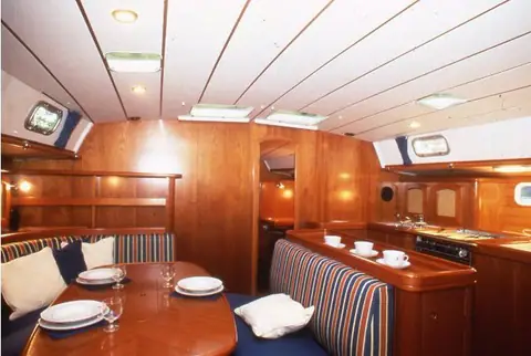 Beneteau 50 saloon with varnished joinery, dining table and striped settees
