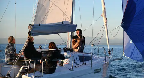 Beneteau First 27 cockpit with crew relaxing under sail at sunset
