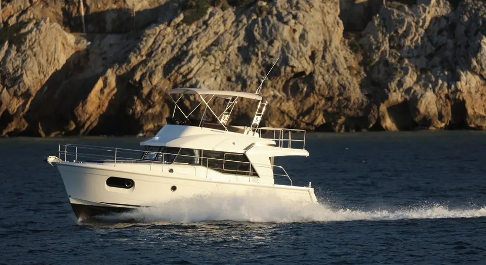 Beneteau Swift Trawler 35 flybridge cruiser running past rocky cliffs