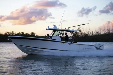 Blackfin 332 CC cruising in profile at sunset with twin outboards