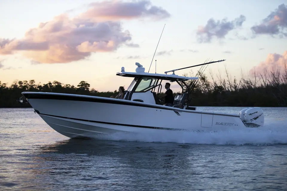 Blackfin 332 CC cruising in profile at sunset with twin outboards