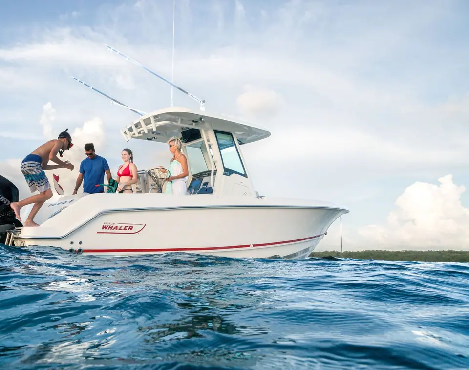 Boston Whaler 250 Outrage at anchor in profile with a family aboard