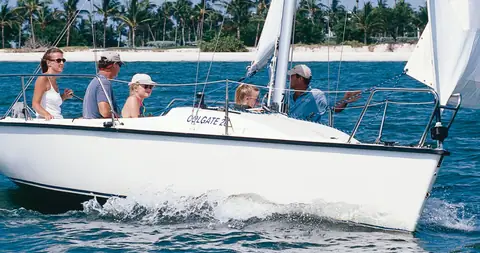 Colgate 26 reaching off a palm lined beach with a family aboard