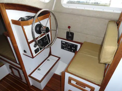 Inside steering station of the Com-Pac 23 Pilothouse with wheel and teak trim