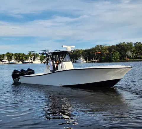 Conch 33 idling near a marina with triple black outboards and a T top