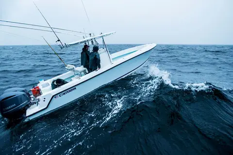 Contender 28T running through a wave with two anglers at the console