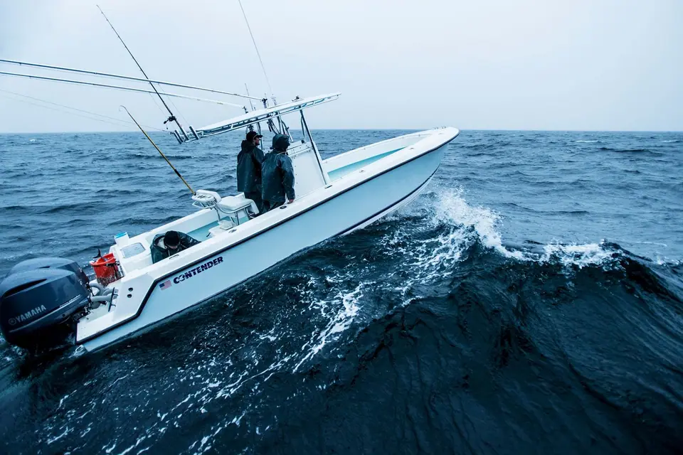 Contender 28T running through a wave with two anglers at the console