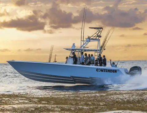 Contender 39 ST with tower running past a sandbar at sunset