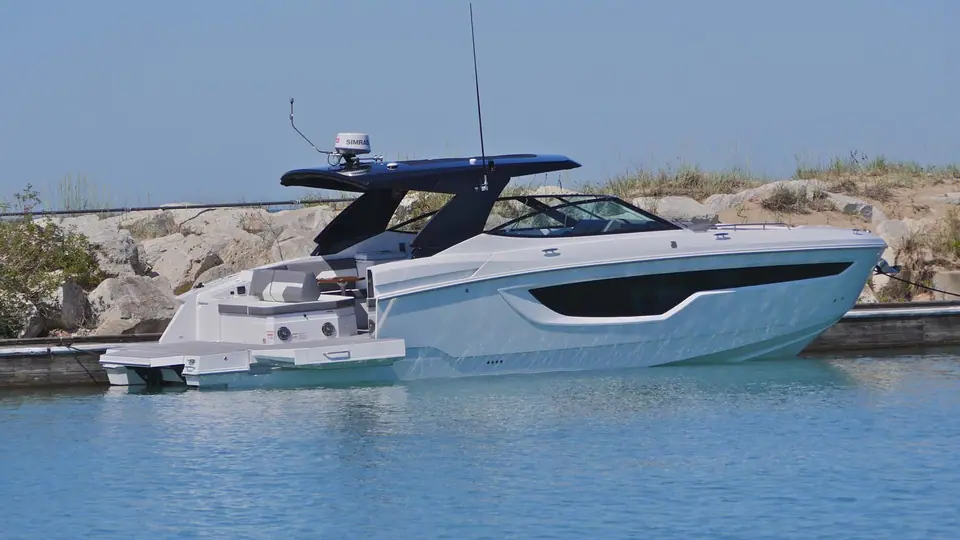 Cruisers Yachts 38 GLS in profile beside a stone breakwater with its hardtop and swim platform