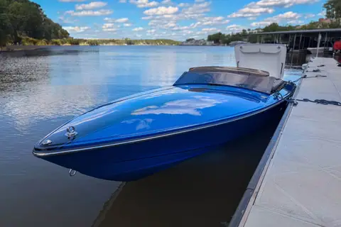 Donzi 22 Classic with a royal blue hull tied alongside a floating dock