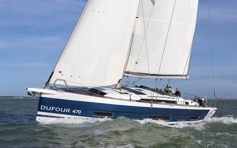 Dufour 470 heeling upwind with the name on its navy hull and full bow sections