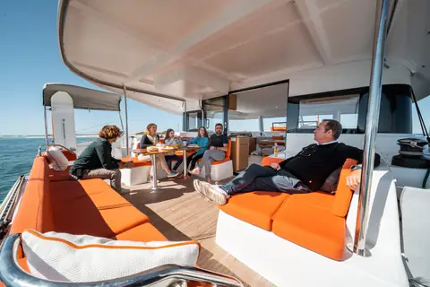 Excess 14 aft cockpit with orange cushions and crew relaxing under the bimini