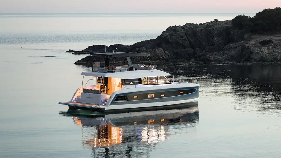 Fountaine Pajot MY 44 power catamaran at anchor at dusk with its flybridge and saloon lit
