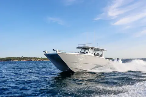Freeman 42 catamaran center console running fast near a rocky shoreline