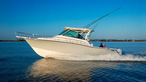 Grady-White Express 370 cruising in profile with its hardtop, outriggers and twin outboards
