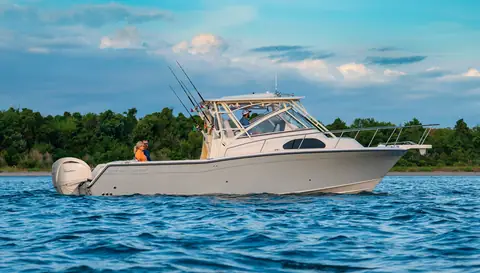 Grady-White Marlin 300 walkaround cruising past a wooded shore with its hardtop and twin outboards