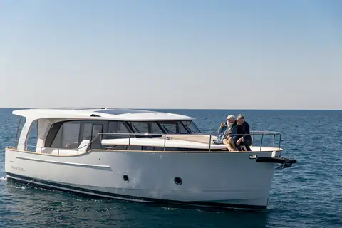 Greenline 40 cruising slowly with a couple seated on the foredeck