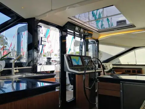 Gunboat 68 inside helm station with a wheel, chartplotter and galley counter in the saloon