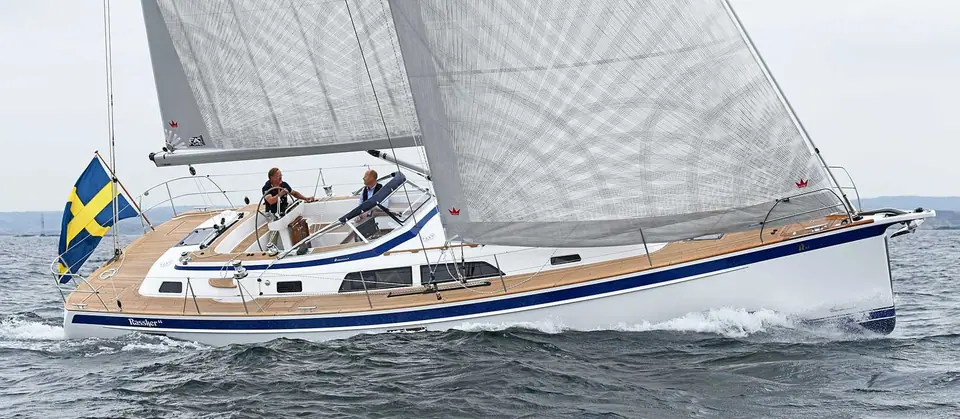 Hallberg-Rassy 44 sailing upwind under main and genoa with two crew in the cockpit