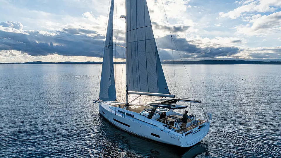 Hanse 460 sailing in light air on calm water, seen from off the stern quarter