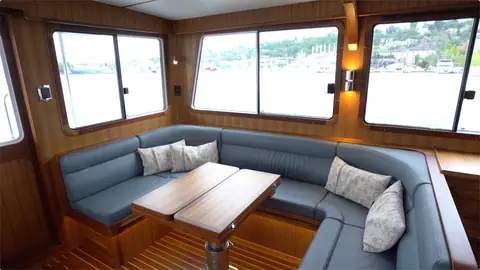 Helmsman 43E Pilothouse salon with a blue U shaped settee, teak table and wide windows