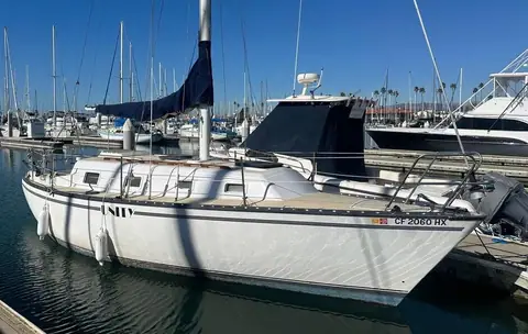 1979 Hunter 30 at a marina slip with a blue sail cover and dodger